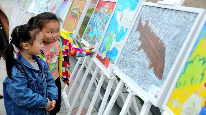加入中华鲟放流活动的儿童自愿者在浏览画作